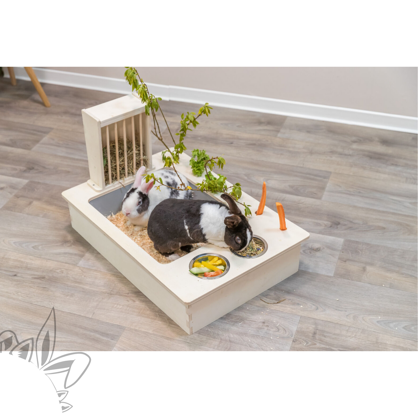 Ratelier litière en bois non traité pour lapin avec bac amovible en plastique, deux gamelles en acier inoxydable et des cavités pour y glisser legumes et branches.